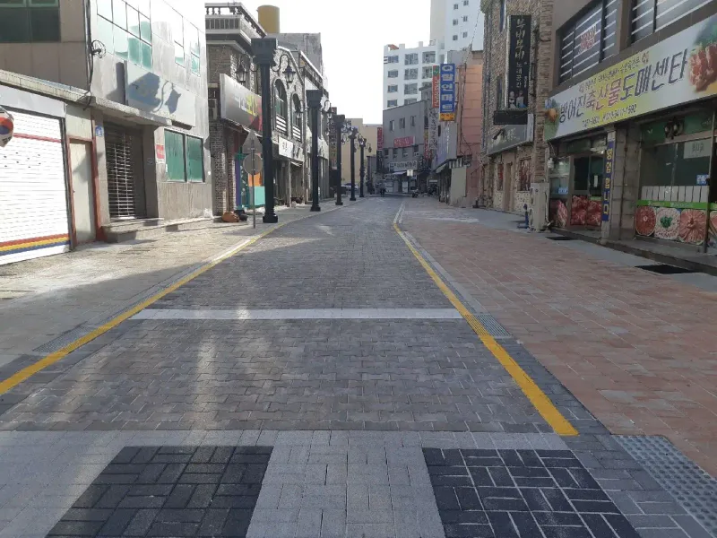 방어진 국제디자인거리 횡단 구간. 회갈색 차도블록 길 앞쪽에 짙은 회색과 밝은 회색 블록으로 구획한 횡단부가 있고 옆 보도는 적갈색이다.