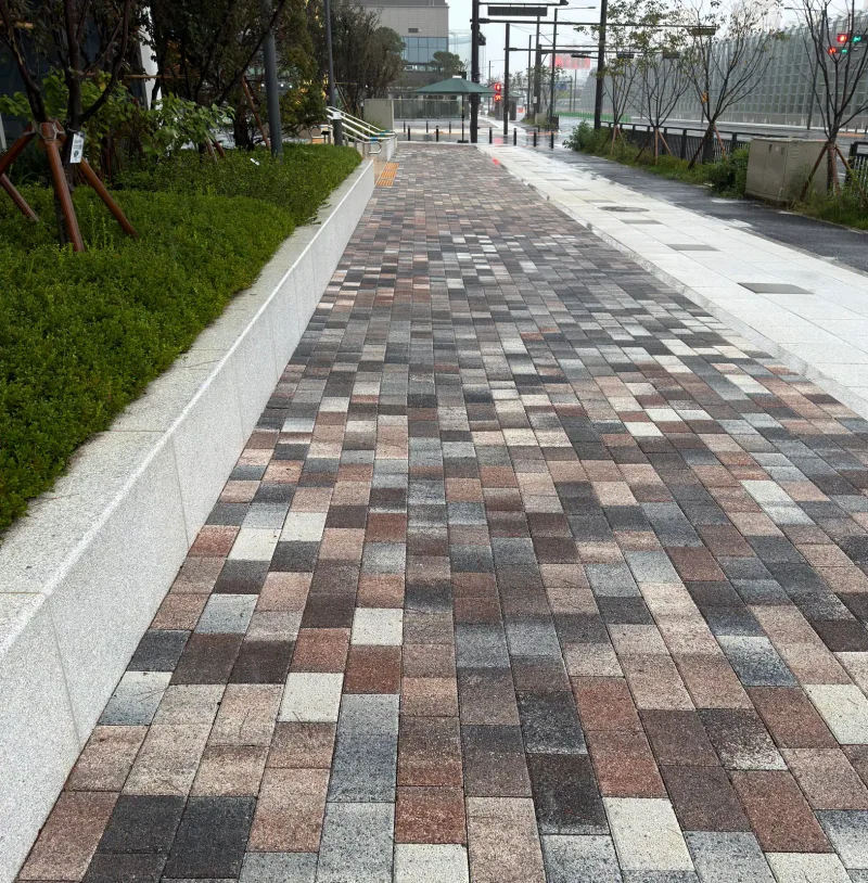 고양 풍동2지구 더샵 엘로이 화단 옆 보행로. 적갈색·회색·흰색이 섞인 블록 길이 화강석 화단 경계를 따라 곧게 뻗는다.
