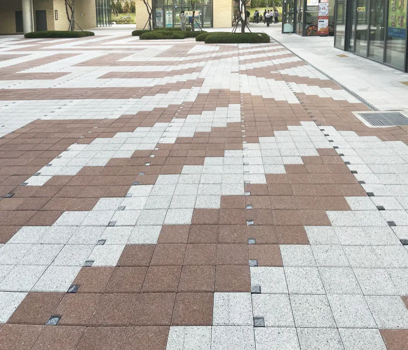 중곡 보건복지행정타운 상가 앞 광장. 적갈색과 밝은 회색 블록이 계단식 지그재그 무늬로 번갈아 깔려 건물 쪽으로 이어진다.