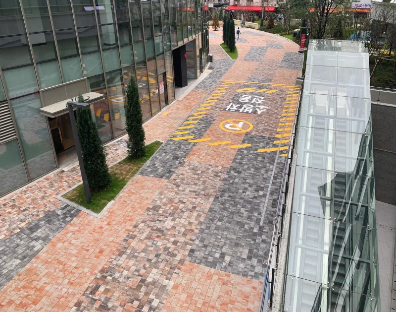 고덕 센트럴 푸르지오 상가 앞 보행로를 위에서 내려다본 모습. 적갈색과 회색 블록이 넓은 띠로 섞여 깔렸고 바닥에 소방차 전용 구역 표시가 있다.
