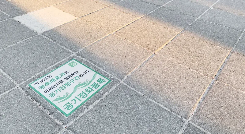 서울랜드 공기정화블록 안내판 근접. 회색 블록 바닥에 '공기정화블록'이라 적힌 초록 안내판이 끼워져 있다.