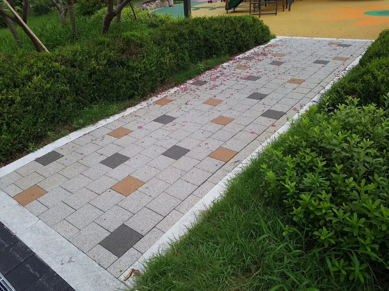 신길 래미안 화단 사이 보행로 근접. 연회색 블록 바탕에 갈색·짙은 회색·베이지 블록이 드문드문 박혀 있다.