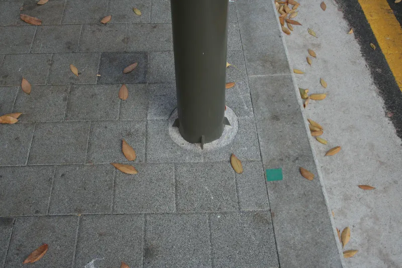 성수문화복지회관 앞 보도 바닥 근접. 기둥 둘레까지 회색 블록이 맞춰 깔려 있고, 옆으로 화강석 경계석과 노란 연석 선이 나란하다.