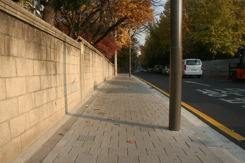 성수문화복지회관 인근 담장 길. 회색 블록이 깔린 보도가 단풍 든 가로수와 높은 담장 사이로 길게 이어진다.