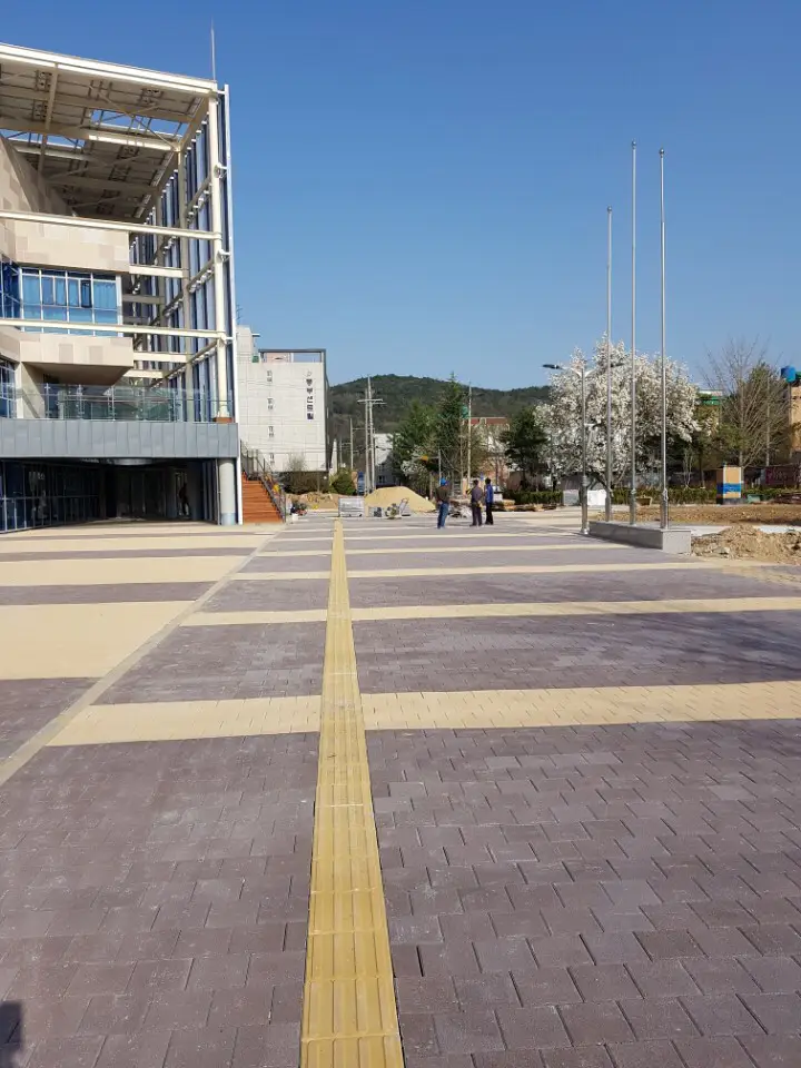 울주 언양읍 청사 앞 광장. 보랏빛 회색 블록 구획 사이를 베이지 블록 띠가 가르고 가운데 노란 점자블록이 청사 건물 쪽으로 곧게 이어진다.