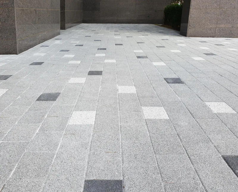 e편한세상 부산항 건물 아래 필로티 통로. 회색 블록 바닥에 흰색·짙은 회색 블록이 드문드문 섞여 깔려 있다.