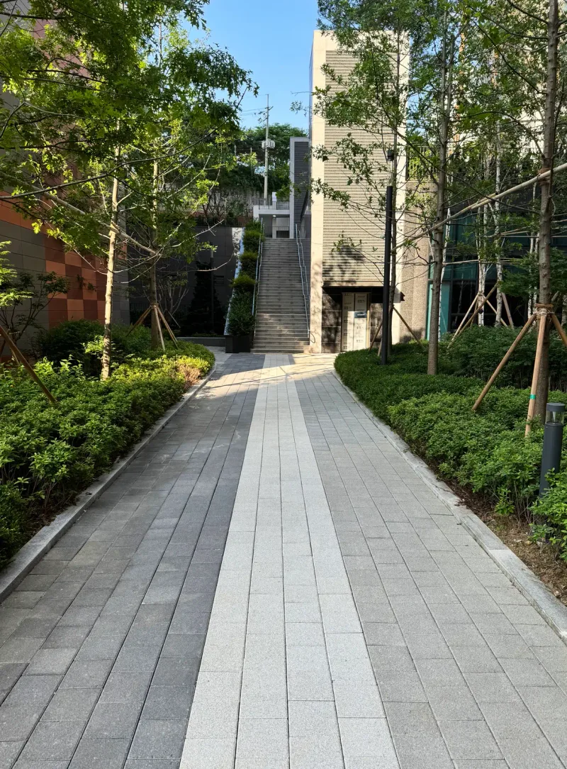 e편한세상 구성역 플랫폼시티 계단으로 이어지는 보행로 세로 사진. 회색 블록 길 가운데에 밝은 블록 띠가 곧게 뻗어 있다.