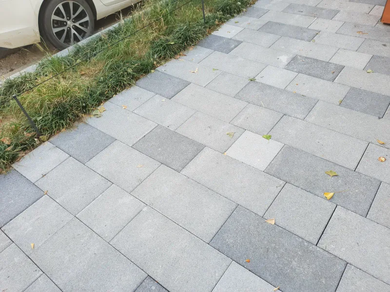 중구 동호로 보도 블록 배치 근접. 밝은 회색·중간 회색·짙은 회색 대형 블록이 크기를 섞어 사선으로 깔린 모습과 화단 경계가 보인다.