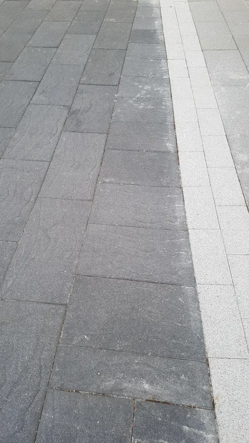 유스트림 광장 블록 근접 세로 사진. 짙은 회색 직사각형 블록 옆으로 밝은 회색 블록 한 줄이 곧게 이어진다.