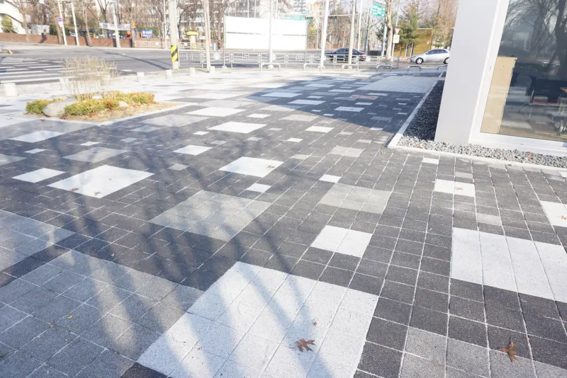 월계 한내도서관 모퉁이 바닥. 흰빛·회색·짙은 회색 정사각형 블록이 크기가 다른 직사각형 면으로 묶여 대비를 이룬다.