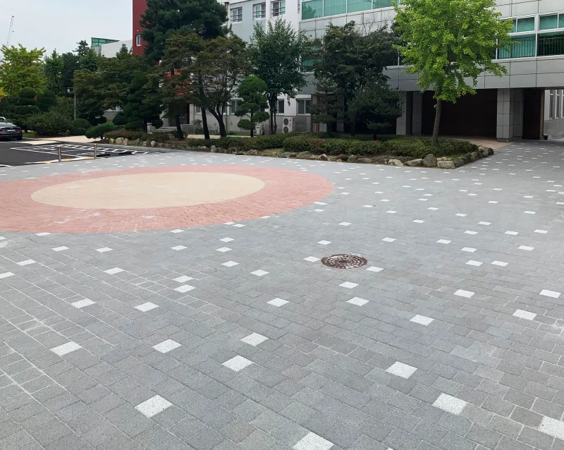 한국체육고등학교 본관 앞 광장. 회색 블록에 흰 블록이 점점이 박혀 있고 한쪽에 붉은 테두리의 베이지색 원형 무늬가 있다.