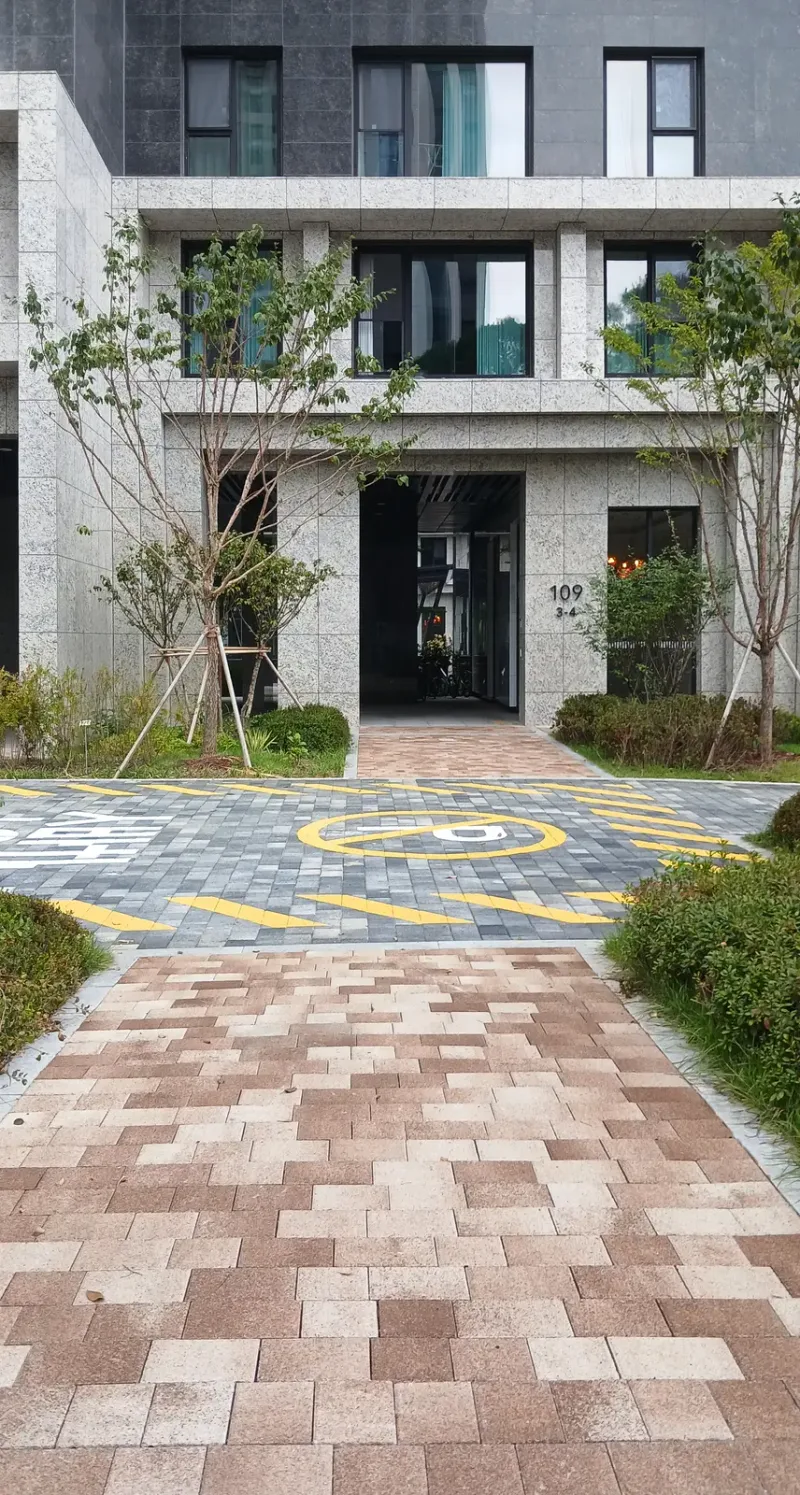 반포 래미안 트리니원 109동 출입구 앞. 분홍·베이지 블록 진입로가 노란 표시를 칠한 회색 블록 길을 지나 현관으로 이어진다.