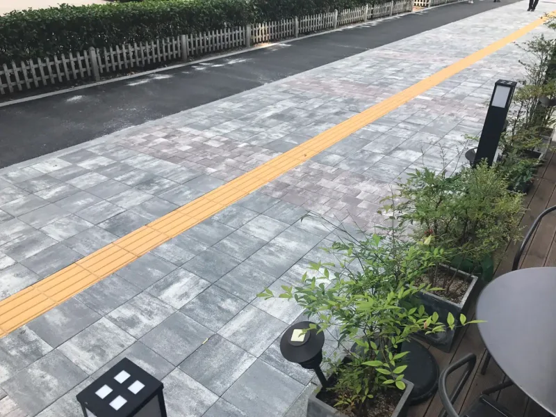 잠실관광특구 카페 앞 보도. 화분과 바닥 조명 옆으로 회색 계열 블록과 대각선으로 지나는 노란 점자블록이 보인다.