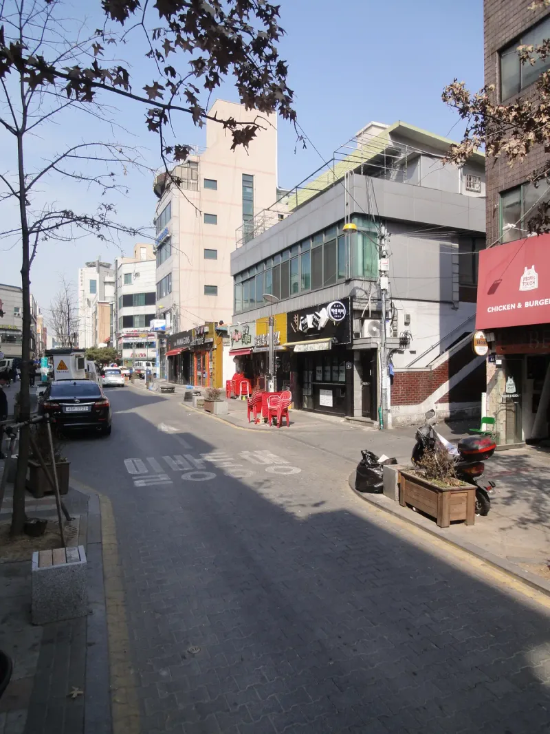 부천 차도블록 구간 보행로. 회색 블록 포장 보도에 붉은 자전거들이 줄지어 놓이고 옆 차도에는 차량이 지나가고 있다.