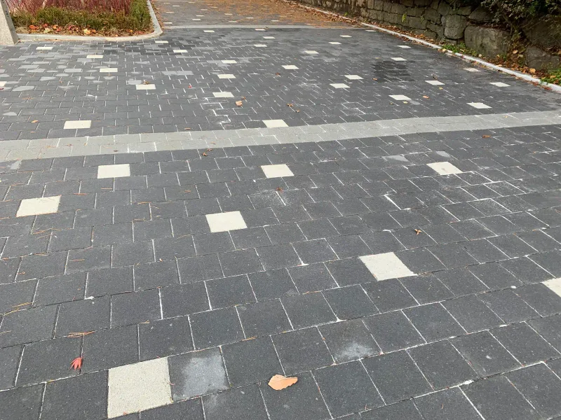 서울대공원 순환도로 블록 근접. 짙은 회색 직사각형 블록 사이로 흰색 블록이 점점이 박히고 밝은 회색 띠가 지난다.