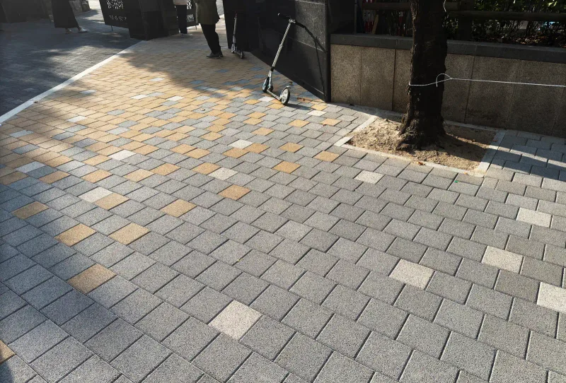 마포 염리초등학교 담장 앞 보도. 회색 블록 바탕에 베이지·흰색 블록이 섞여 깔리고 가로수 둘레가 흙으로 남아 있다.