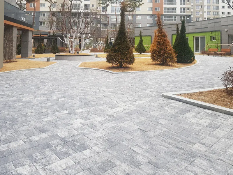 동탄2 아이파크 단지 광장. 회색·흰색이 섞인 블록이 넓게 깔리고 원뿔형 나무를 심은 화단이 광장 가운데를 나눈다.