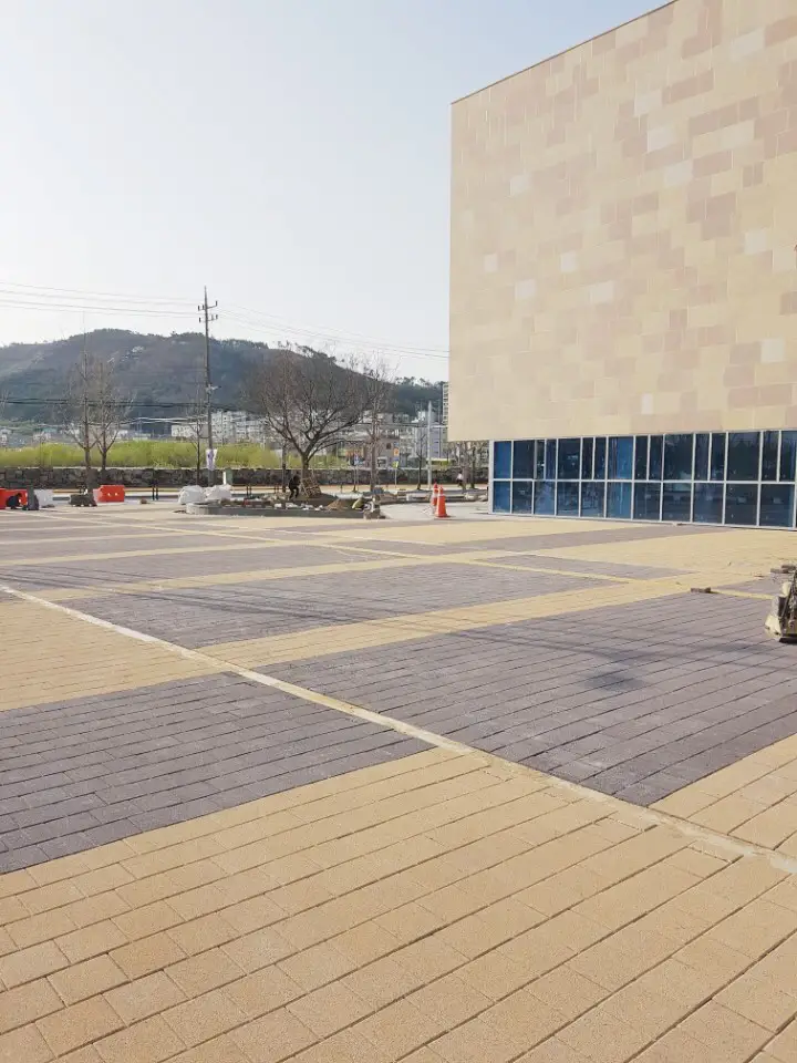 언양읍 청사 별관 옆 광장. 베이지 블록 띠와 보랏빛 회색 블록 구획이 번갈아 깔린 바닥이 석재 외벽 건물 앞까지 넓게 이어진다.