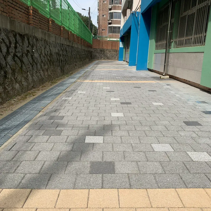 북서울중학교 통로 앞쪽의 베이지색 블록 띠. 그 너머로 짙은 회색과 밝은 회색 블록이 흩어져 섞인 회색 포장길이 뻗어 있다.