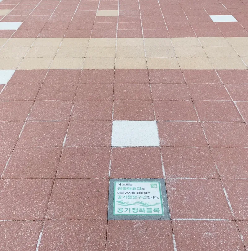 서울랜드 적갈색 블록 구간 근접. 적갈색 정사각형 블록 사이에 흰 블록과 공기정화블록 안내판이 매립되어 있다.
