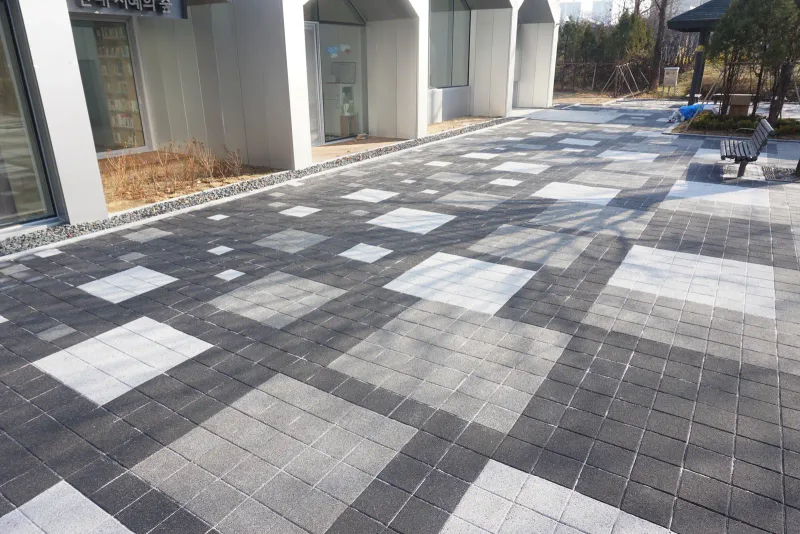 월계 한내도서관 출입구 앞 바닥 근접 모습. 짙은 회색 블록 바탕에 흰빛·회색 블록 사각 면이 조각보처럼 섞여 있다.