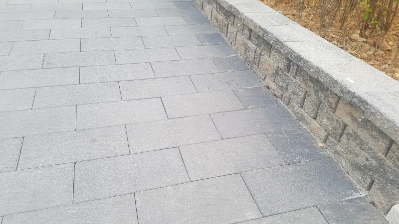 느티나무길 화단 벽을 따라 본 모습. 회색 대형 블록이 줄눈을 엇갈려 곧게 깔리고 오른쪽에 쌓은 석재 화단 벽이 이어진다.